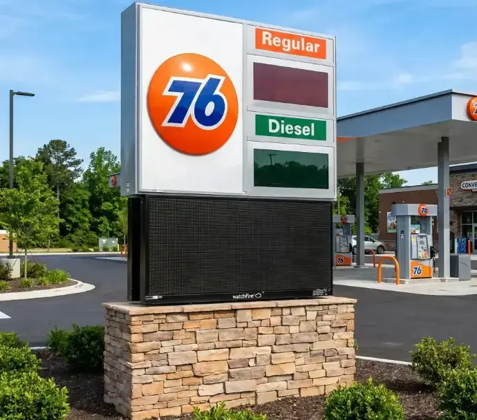 A 76 gas station sign with an electronic price board on a stone base.